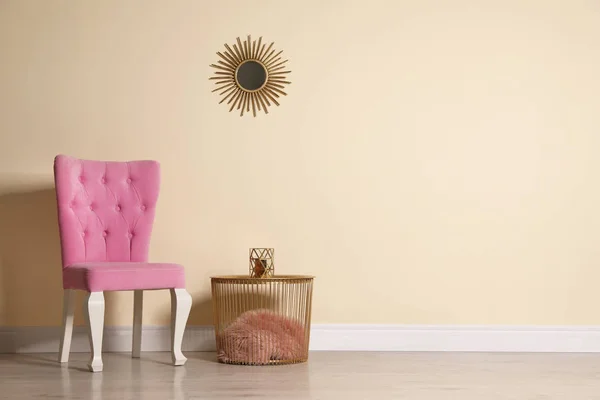 Elegante cadeira rosa e mesa perto da parede bege no quarto. Espaço para texto — Fotografia de Stock