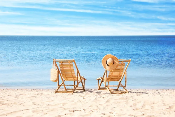 Cadeiras de madeira na praia de areia perto do mar — Fotografia de Stock