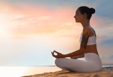 Genç kadın plajda zen meditasyon uyguluyor. Metin için alan