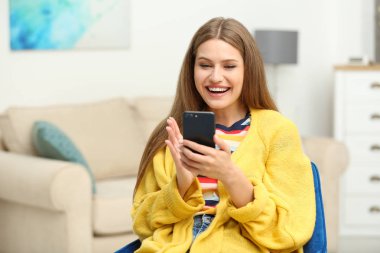 Mutlu genç kadın evde akıllı telefon kullanarak online piyango oynuyor
