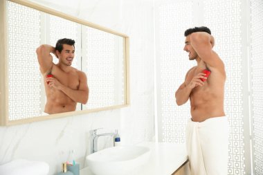 Yakışıklı genç adam banyoda deodorant uygulamak