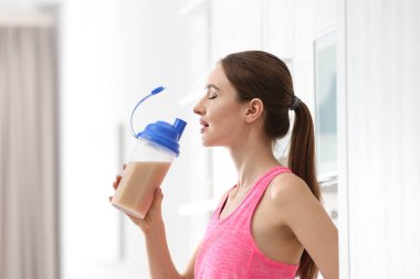 Atletik genç kadın mutfakta protein shake içme