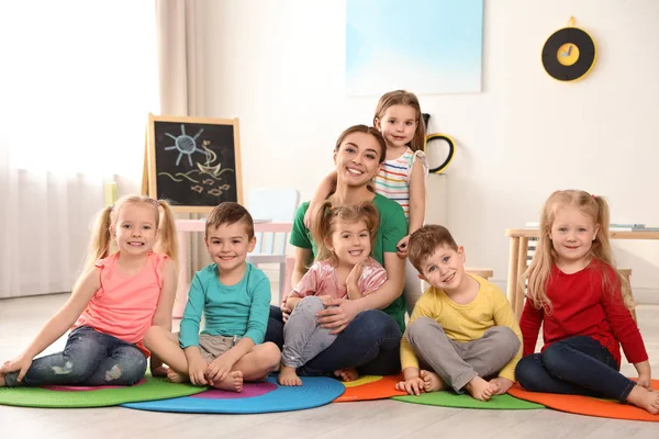 Преподаватель детского сада с группой детей в игровой комнате. Активность в помещении — стоковое фото