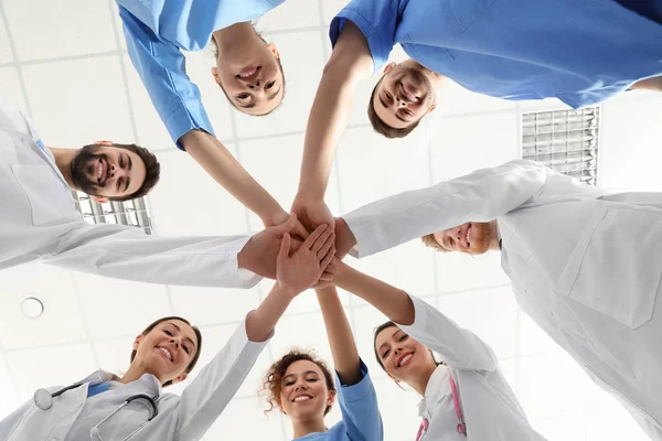 Команда медицинских работников держится за руки в больнице, вид снизу. Концепция единства — стоковое фото