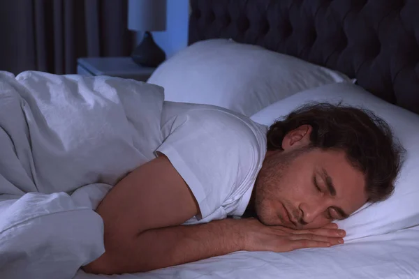 Un joven guapo durmiendo en la almohada por la noche. Hora de dormir — Foto de Stock