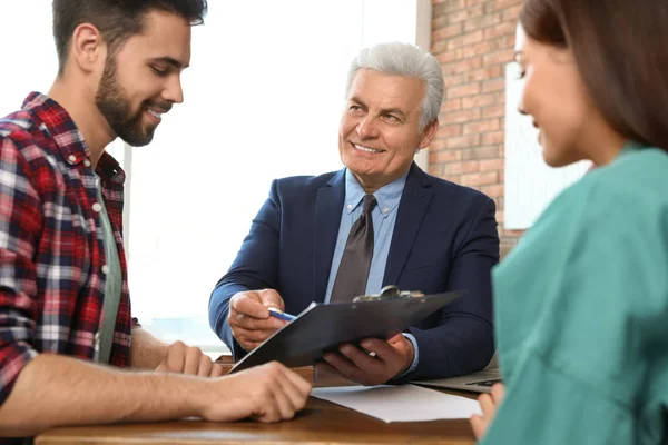 Leitender Notar arbeitet mit jungem Paar im Büro — Stockfoto