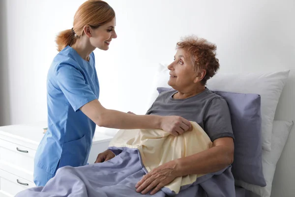 Медсестра допомагає літній жінці в ліжку в приміщенні — стокове фото