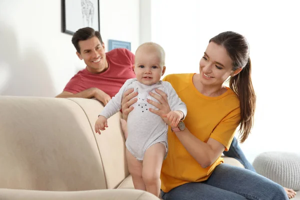 Padres felices con bebé en el sofá en la sala de estar —  Fotos de Stock