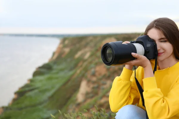 Női fotós figyelembe kép gyönyörű táj professzionális kamerával a zöld dombon. Szóköz a szöveghez — Stock Fotó
