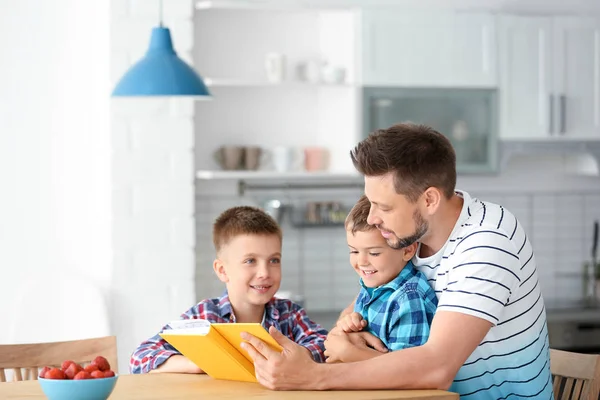 Vader en zijn zonen lezen interessant boek in de keuken. Ruimte voor tekst — Stockfoto