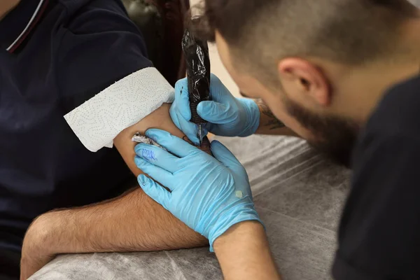 Maestro profesional del tatuaje trabajando con el cliente en el salón — Foto de Stock