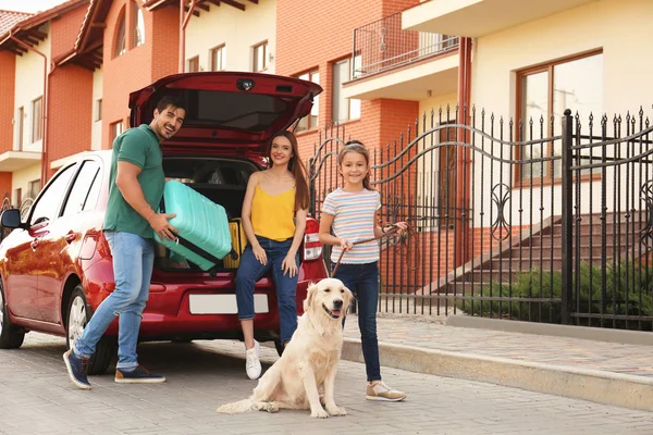 Famille heureuse avec chien et valise près de la voiture dans la rue — Photo