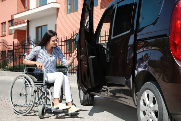 車椅子の若い女性は、屋外で彼女のバンのドアを開きます — ストック写真