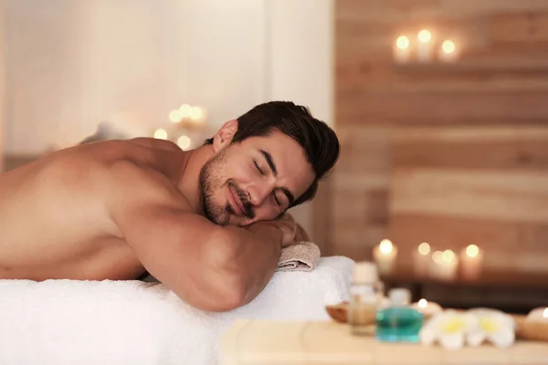 Knappe jonge man ontspannen op massagetafel in Spa Salon, ruimte voor tekst — Stockfoto