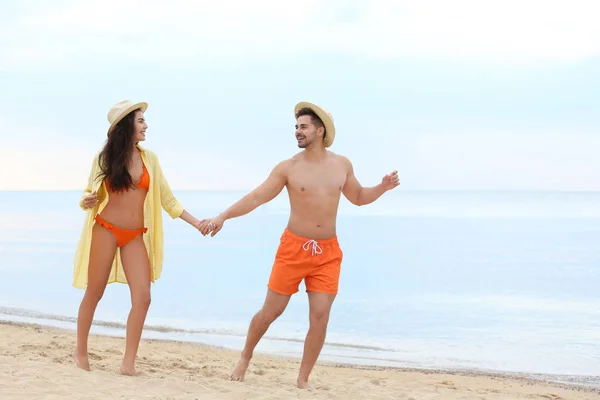 Glückliches junges Paar, das zusammen am Strand am Meer spaziert — Stockfoto