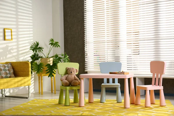 Стильный интерьер игровой комнаты со столом, стульями и диваном — стоковое фото