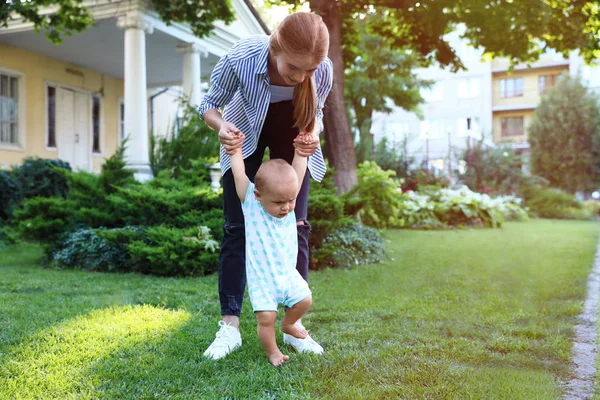 Teen nounou avec mignon bébé sur herbe verte à l'extérieur — Photo