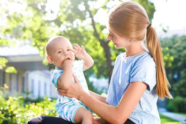 Teen Nanny med söt baby utomhus på solig dag — Stockfoto