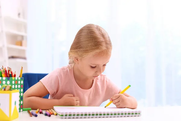 Cute little left-handed girl drawing at table in room — Stock Photo, Image