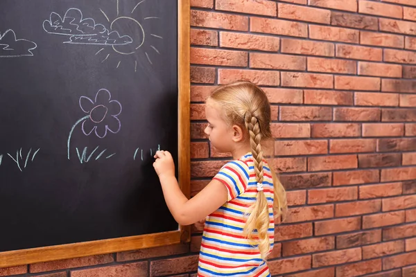 Aranyos kis balkezes lány rajzot Chalkboard közelében téglafal — Stock Fotó