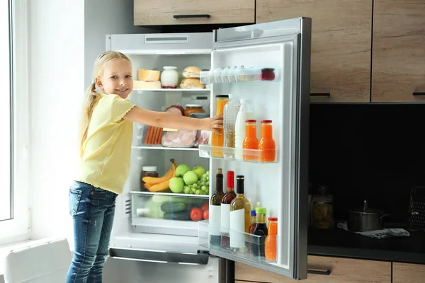 Девушка берет бутылку с соком из холодильника на кухне — стоковое фото