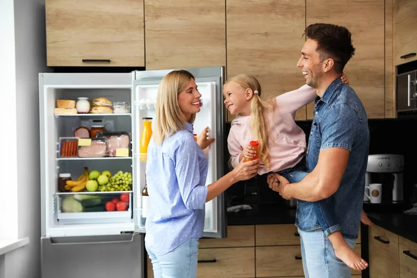 Boldog család egy üveg lé közelében hűtőszekrény a konyhában — Stock Fotó