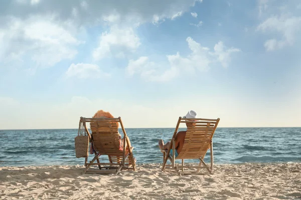 Ungt par koppla av i solstolar på stranden nära havet — Stockfoto