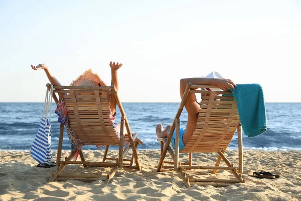 Jong stel ontspannen in ligstoelen op het strand in de buurt van zee — Stockfoto