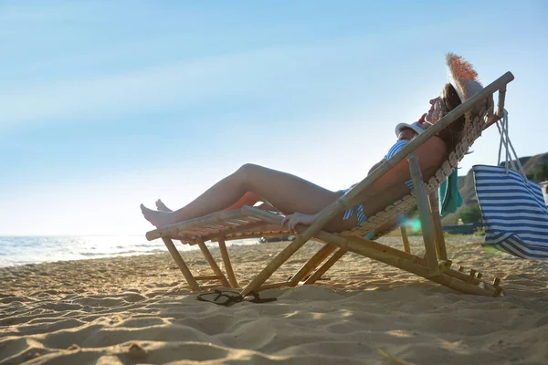 Pareja joven relajándose en tumbonas en la playa cerca del mar — Foto de Stock
