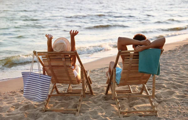 Junges Paar entspannt in Liegestühlen am Strand in der Nähe des Meeres — Stockfoto