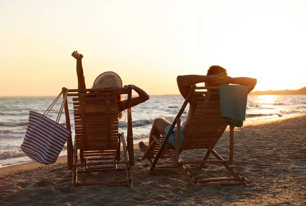 Jong stel ontspannen in ligstoelen op het strand in de buurt van zee — Stockfoto