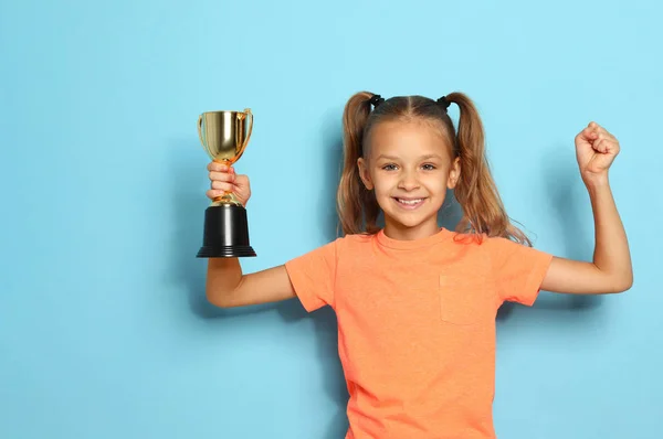Gelukkig meisje met gouden winnende Cup op blauwe achtergrond — Stockfoto