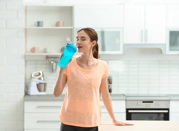 Atlética joven bebiendo batido de proteínas en la cocina —  Fotos de Stock