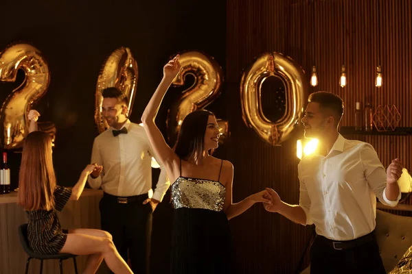 Młodzi ludzie świętują Nowy rok w klubie. Złote 2020 balony na tle — Zdjęcie stockowe