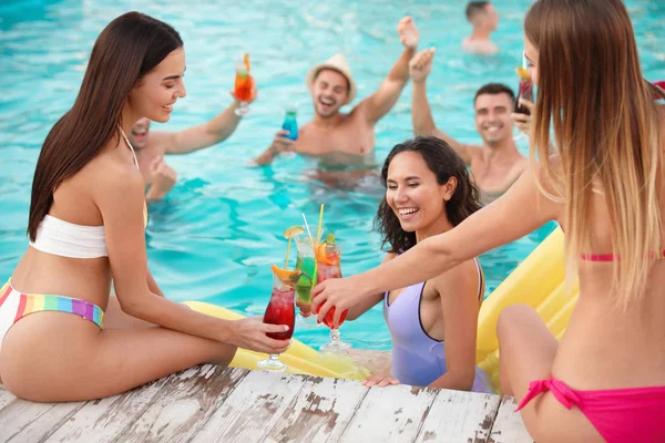 Felices jóvenes amigos con refrescantes cócteles disfrutando de la fiesta en la piscina — Foto de Stock
