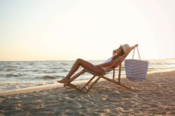 Young woman relaxing in deck chair on beach Stock Photo