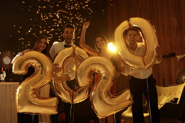 Young people with golden 2020 balloons celebrating New Year in club Royalty Free Stock Images