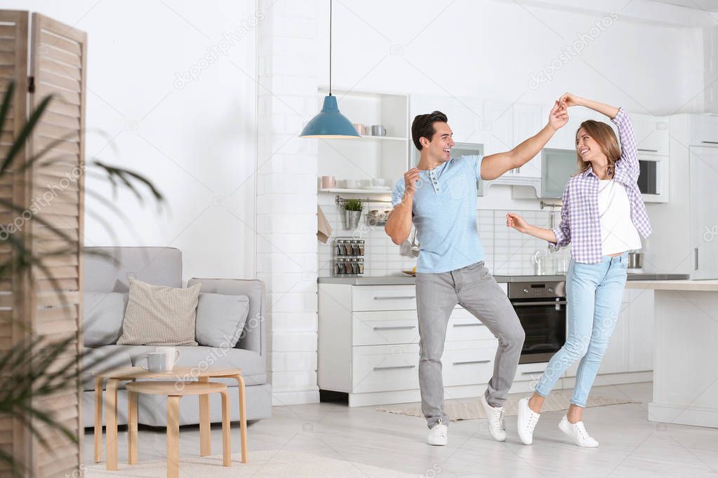 Beautiful young couple dancing in kitchen at home