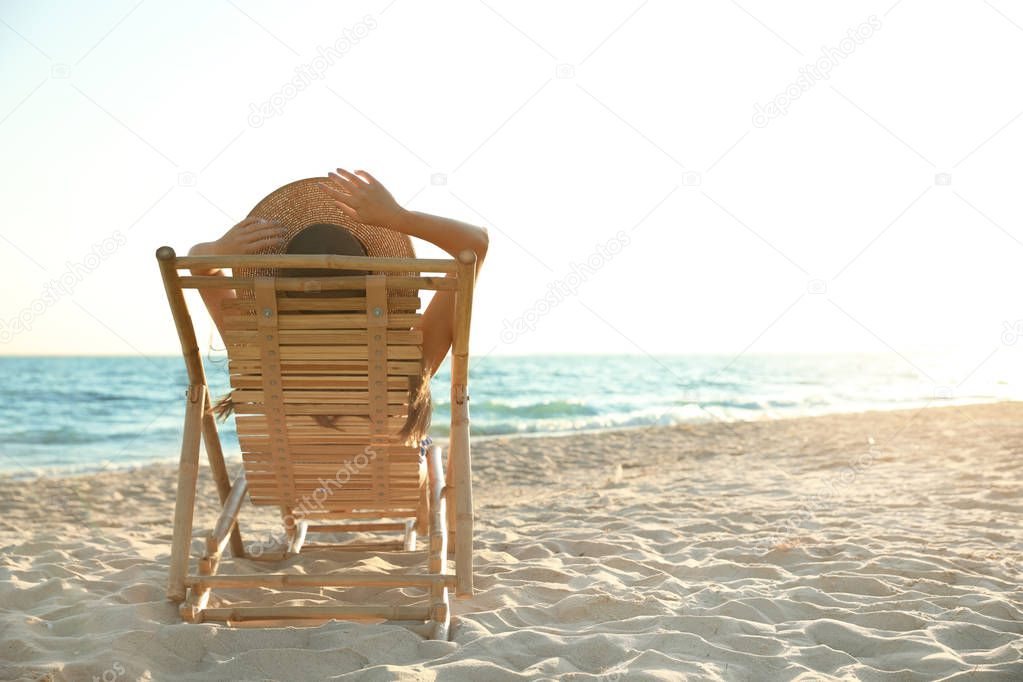 Young woman relaxing in deck chair on beach