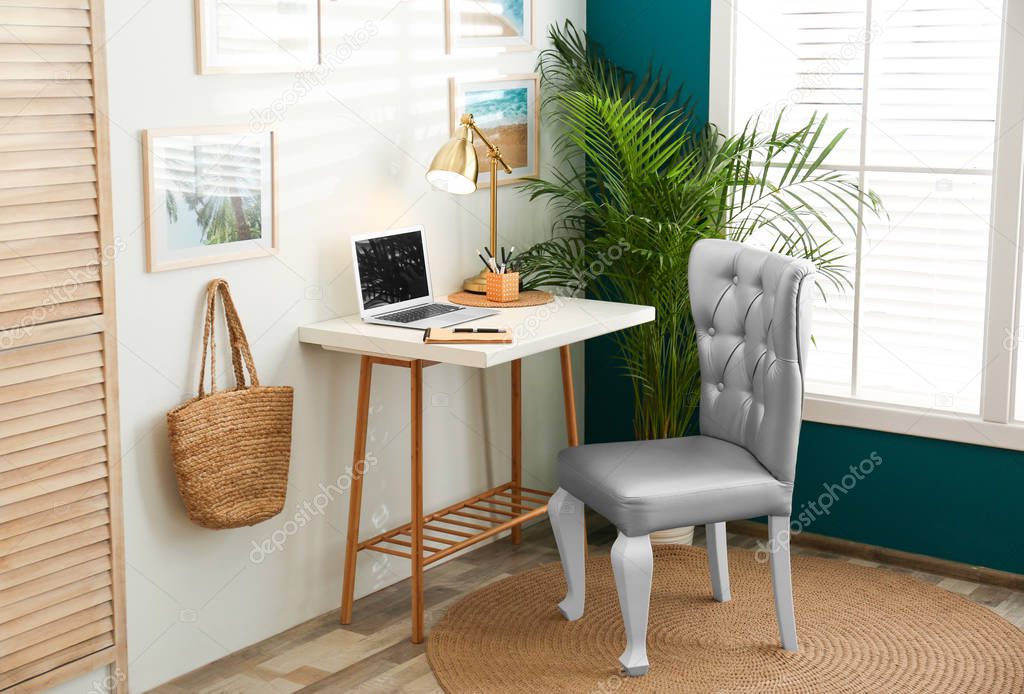 Stylish home workplace with elegant grey chair near window. Interior design