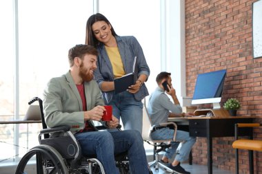 Ofiste meslektaşları ile tekerlekli sandalyede genç adam