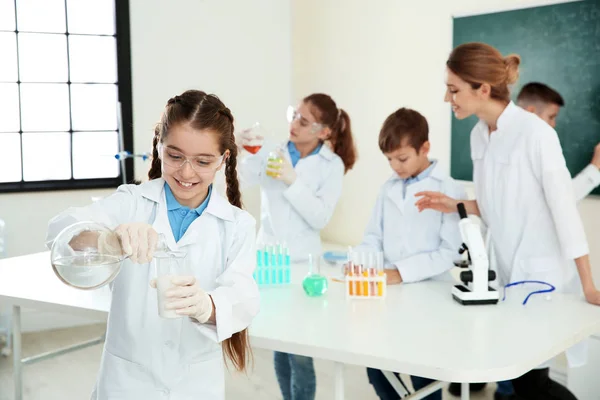 Schülerin macht Experiment mit Lehrerin und Schülern im Chemieunterricht — Stockfoto