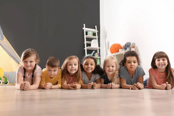 Söta små barn som ligger på golvet på dagis. Inomhusaktivitet — Stockfoto