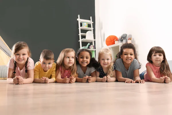 Niedliche kleine Kinder, die im Kindergarten auf dem Boden liegen. Aktivitäten in Innenräumen — Stockfoto