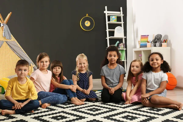 Niedliche kleine Kinder, die im Kindergarten auf dem Fußboden sitzen. Aktivitäten in Innenräumen — Stockfoto