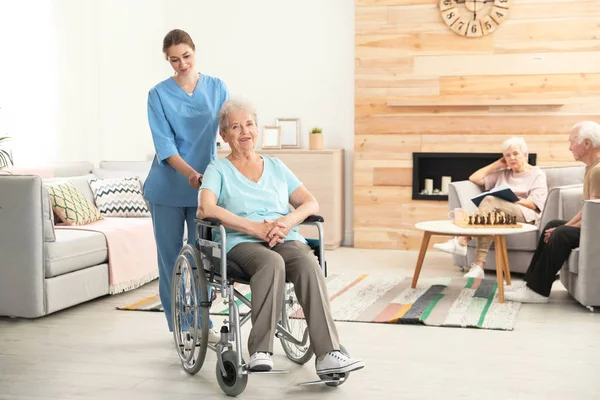 Enfermeira assistindo a idosa em cadeira de rodas em casa de repouso. Espaço para texto — Fotografia de Stock