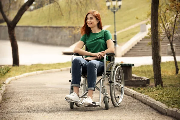 Jovem mulher em cadeira de rodas no parque no dia ensolarado — Fotografia de Stock