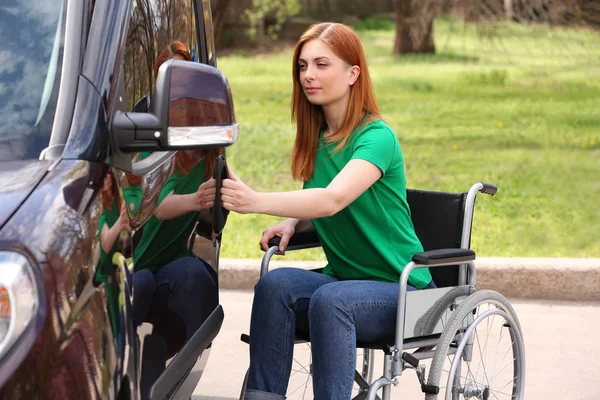 車椅子の女性は、屋外で彼女のバンのドアを開きます — ストック写真