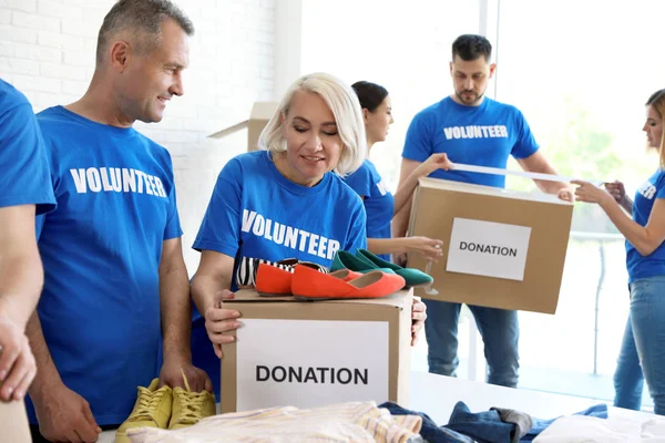 Equipo de voluntarios recogiendo donaciones en cajas interiores — Foto de Stock