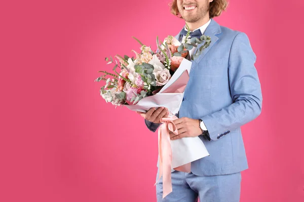 Homem em terno elegante segurando lindo buquê de flores no fundo rosa, close-up. Espaço para texto — Fotografia de Stock